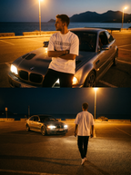 Man standing next to a BMW car in a parking lot with mountains in the background